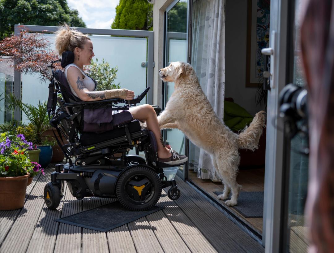 Kvinna i elektrisk rullstol med hund.